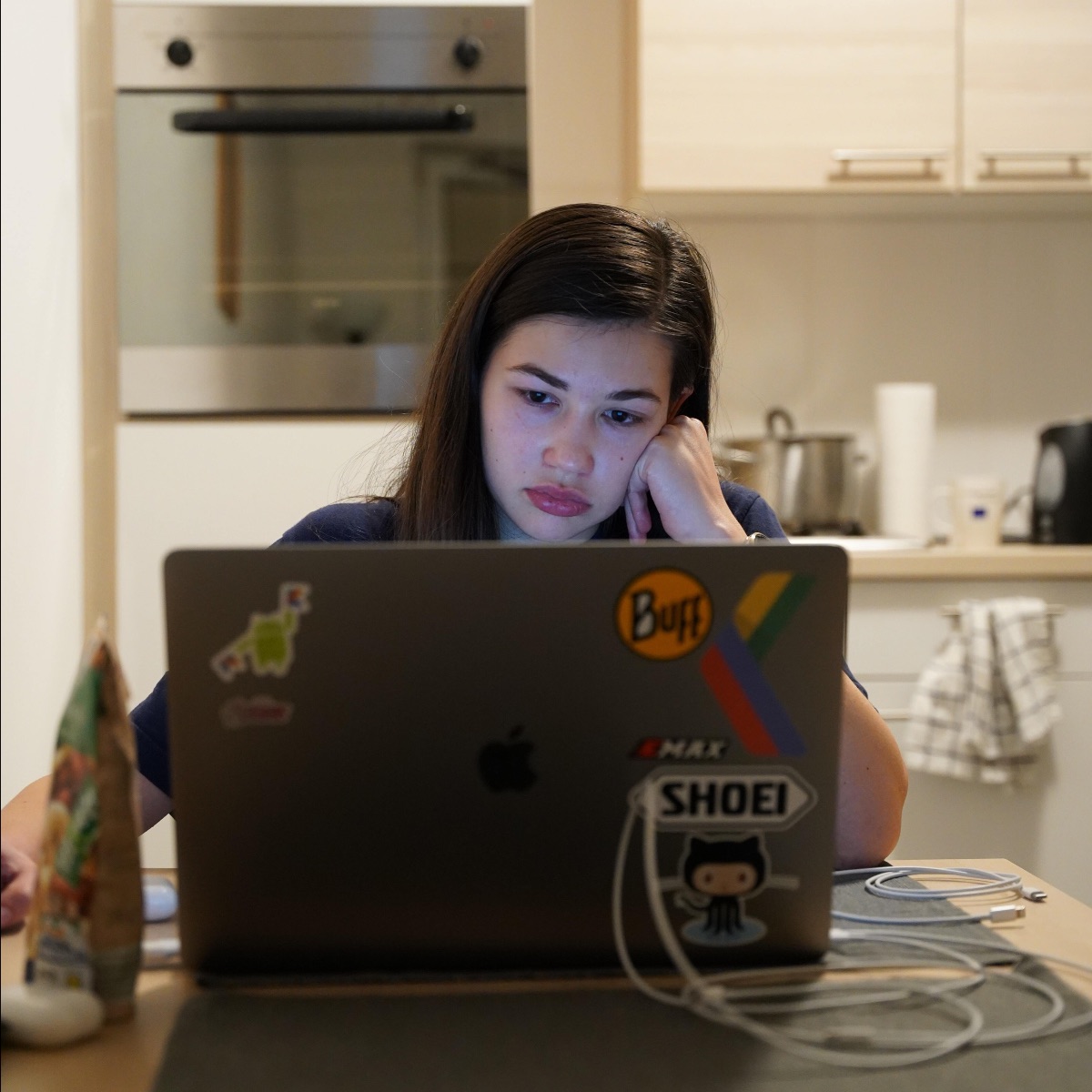 Person sat at their laptop, looking dispirited with their head rested on their hand.