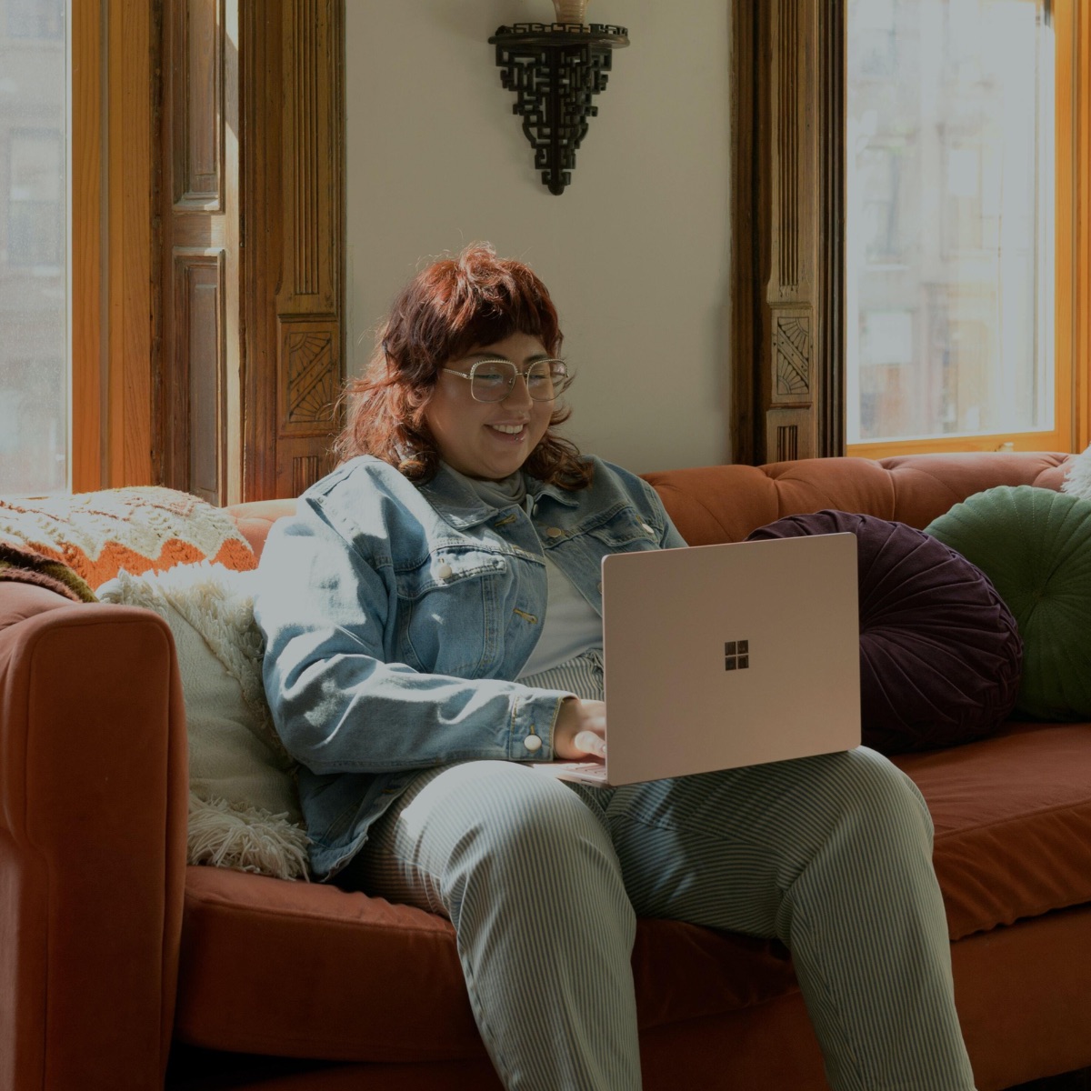 Person sitting on sofa on laptop, smiling